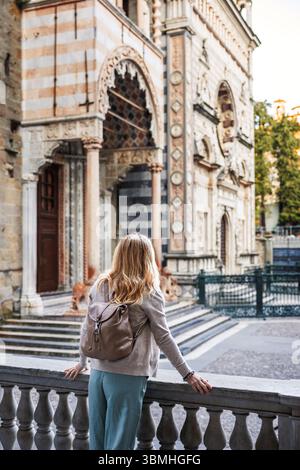 Frau, die die mittelalterliche Architektur der Basilika di Santa Maria Maggiore in Citta Alta Bergamo, Italien, erkundet. Städtereise in Europa Stockfoto