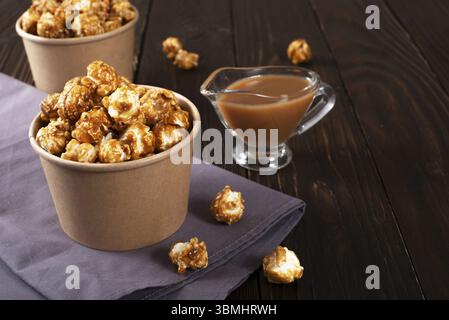 Karamellisiertes Popcorn in Papiereimer auf Holztisch Stockfoto