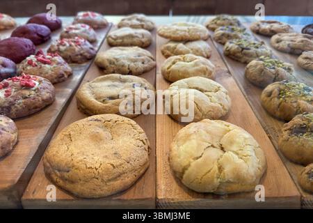 Runde, frisch gebackene Plätzchen mit verschiedenen Zutaten, ausgestellt auf einer rustikalen Holzoberfläche. Stockfoto