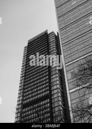 Vereinigtes Königreich, London, 4. Juli 2025. Schwarz-weiß-Ansicht auf zwei moderne Bürohochhäuser in London mit vertikalen Glasfassaden und geometrischem Pat Stockfoto