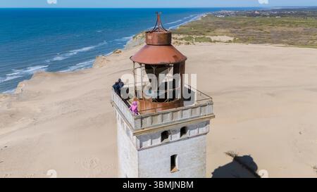 Besucher bewundern atemberaubende Ausblicke von der Spitze eines berühmten Leuchtturms in Dänemark. Dieses Juwel an der Küste bietet eine einzigartige Perspektive auf den endlosen Strand und das Meer, Rubjerg Knude, Nordjütland Stockfoto
