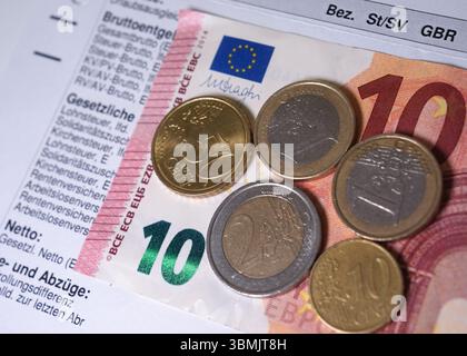 Hamburg, Deutschland. Juni 2025. ILLUSTRATION - Euro- und Cent-Münzen liegen auf einem Lohnbeleg und auf einem 10-Euro-Schein und machen zusammen 14,60 Euro aus. Der Mindestlohn in Deutschland soll zum 1. Januar 2027 in zwei Stufen auf 14,60 Euro steigen. Quelle: Marcus Brandt/dpa/Alamy Live News Stockfoto