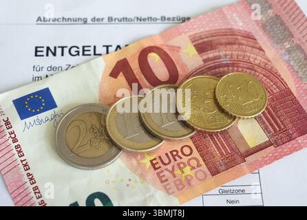 Hamburg, Deutschland. Juni 2025. ILLUSTRATION - Euro- und Cent-Münzen liegen auf einem Lohnbeleg und auf einem 10-Euro-Schein und machen zusammen 14,60 Euro aus. Der Mindestlohn in Deutschland soll zum 1. Januar 2027 in zwei Stufen auf 14,60 Euro steigen. Quelle: Marcus Brandt/dpa/Alamy Live News Stockfoto