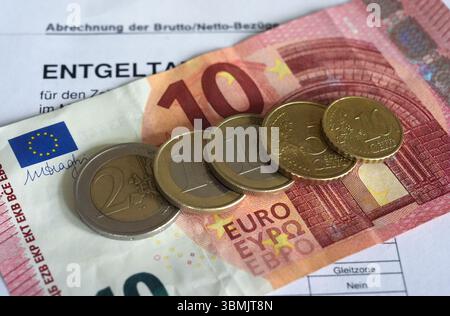Hamburg, Deutschland. Juni 2025. ILLUSTRATION - Euro- und Cent-Münzen liegen auf einem Lohnbeleg und auf einem 10-Euro-Schein und machen zusammen 14,60 Euro aus. Der Mindestlohn in Deutschland soll zum 1. Januar 2027 in zwei Stufen auf 14,60 Euro steigen. Quelle: Marcus Brandt/dpa/Alamy Live News Stockfoto