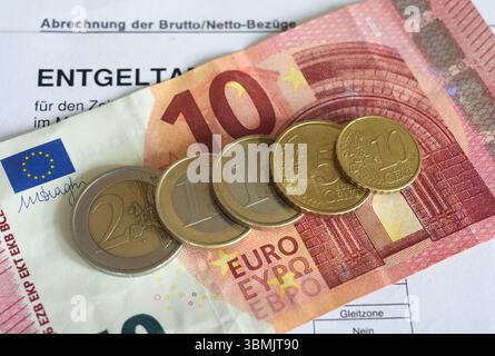 Hamburg, Deutschland. Juni 2025. ILLUSTRATION - Euro- und Cent-Münzen liegen auf einem Lohnbeleg und auf einem 10-Euro-Schein und machen zusammen 14,60 Euro aus. Der Mindestlohn in Deutschland soll zum 1. Januar 2027 in zwei Stufen auf 14,60 Euro steigen. Quelle: Marcus Brandt/dpa/Alamy Live News Stockfoto