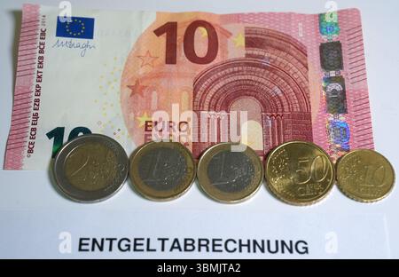 Hamburg, Deutschland. Juni 2025. ILLUSTRATION - Euro- und Cent-Münzen liegen auf einem Lohnbeleg und auf einem 10-Euro-Schein und machen zusammen 14,60 Euro aus. Der Mindestlohn in Deutschland soll zum 1. Januar 2027 in zwei Stufen auf 14,60 Euro steigen. Quelle: Marcus Brandt/dpa/Alamy Live News Stockfoto