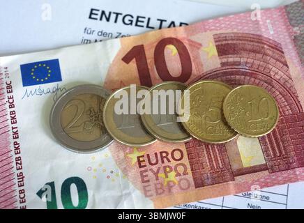 Hamburg, Deutschland. Juni 2025. ILLUSTRATION - Euro- und Cent-Münzen liegen auf einem Lohnbeleg und auf einem 10-Euro-Schein und machen zusammen 14,60 Euro aus. Der Mindestlohn in Deutschland soll zum 1. Januar 2027 in zwei Stufen auf 14,60 Euro steigen. Quelle: Marcus Brandt/dpa/Alamy Live News Stockfoto