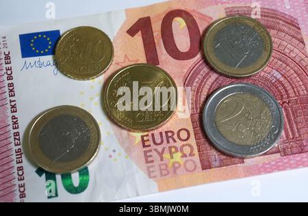 Hamburg, Deutschland. Juni 2025. ILLUSTRATION - Euro- und Cent-Münzen liegen auf einem Lohnbeleg und auf einem 10-Euro-Schein und machen zusammen 14,60 Euro aus. Der Mindestlohn in Deutschland soll zum 1. Januar 2027 in zwei Stufen auf 14,60 Euro steigen. Quelle: Marcus Brandt/dpa/Alamy Live News Stockfoto