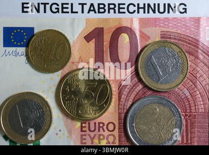 Hamburg, Deutschland. Juni 2025. ILLUSTRATION - Euro- und Cent-Münzen liegen auf einem Lohnbeleg und auf einem 10-Euro-Schein und machen zusammen 14,60 Euro aus. Der Mindestlohn in Deutschland soll zum 1. Januar 2027 in zwei Stufen auf 14,60 Euro steigen. Quelle: Marcus Brandt/dpa/Alamy Live News Stockfoto