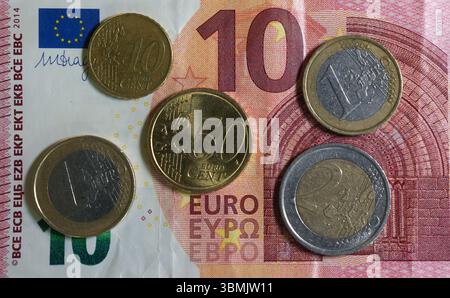 Hamburg, Deutschland. Juni 2025. ILLUSTRATION - Euro- und Cent-Münzen liegen auf einem Lohnbeleg und auf einem 10-Euro-Schein und machen zusammen 14,60 Euro aus. Der Mindestlohn in Deutschland soll zum 1. Januar 2027 in zwei Stufen auf 14,60 Euro steigen. Quelle: Marcus Brandt/dpa/Alamy Live News Stockfoto