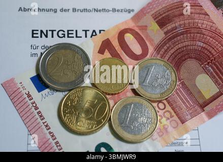 Hamburg, Deutschland. Juni 2025. ILLUSTRATION - Euro- und Cent-Münzen liegen auf einem Lohnbeleg und auf einem 10-Euro-Schein und machen zusammen 14,60 Euro aus. Der Mindestlohn in Deutschland soll zum 1. Januar 2027 in zwei Stufen auf 14,60 Euro steigen. Quelle: Marcus Brandt/dpa/Alamy Live News Stockfoto