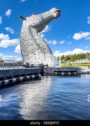 Majestätische große Pferdekopf-Skulptur, bekannt als Kelpies, spiegelt sich im Wasser unter einem blauen bewölkten Himmel in einem Park in Falkirk schottland Stockfoto