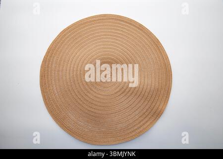 Runder Tischset mit Strohhalm mit konzentrischem Muster auf weißem Hintergrund, umweltfreundliche Einrichtung für Küche und Esszimmer, Blick von oben. Stockfoto