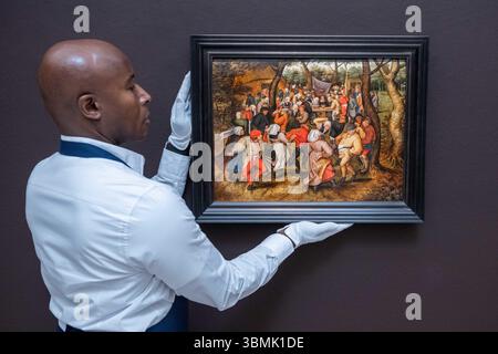 London, England, Großbritannien. Juni 2025. Ein Mitarbeiter von Sotheby's stellt den Outdoor Wedding Dance von Pieter Brueghel dem Jüngeren während der Pressevorschau für die Old Masters Auktion bei Sotheby's in London vor. Das Gemälde wird auf GBP800.000'''1.200.000 geschätzt. (Kreditbild: © Thomas Krych/ZUMA Press Wire) NUR REDAKTIONELLE VERWENDUNG! Nicht für kommerzielle ZWECKE! Stockfoto