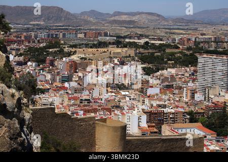 Panoramablick auf die Stadt Alicante mit Stierkampfarena, städtischen Gebäuden und Bergen im Hintergrund unter klarem Himmel. Stockfoto