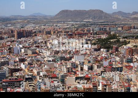 Panoramablick auf die Stadt Alicante mit Stierkampfarena, städtischen Gebäuden und Bergen im Hintergrund unter klarem Himmel. Stockfoto