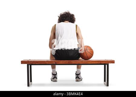 Rückansicht eines müden Basketballspielers, der auf einer Bank sitzt und einen Ball auf weißem Hintergrund isoliert hat Stockfoto