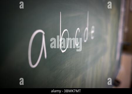 Kleinbuchstaben sind mit weißer Kreide auf die Tafel geschrieben. Stockfoto