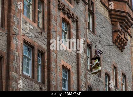 Ein eigentümlicher Anblick: Schuhe, die an einem Draht an einer traditionellen Stadtfassade hängen. Stockfoto