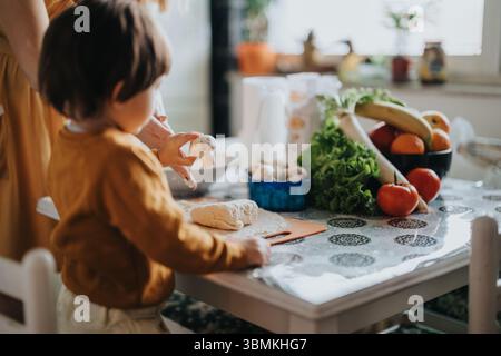 Mutter und Kind bereiten gemeinsam zu Hause eine gesunde Mahlzeit vor, wobei frische Zutaten und Teamarbeit präsentiert werden Stockfoto