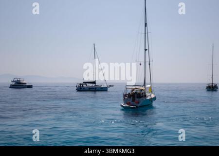 Mehrere Boote segeln auf dem ruhigen, offenen blauen Meer unter einem klaren Himmel Stockfoto