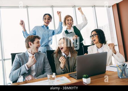 Begeistertes Team feiert Erfolg bei einem Meeting zur Zusammenarbeit in einem modernen Umfeld mit verschiedenen Fachleuten Stockfoto