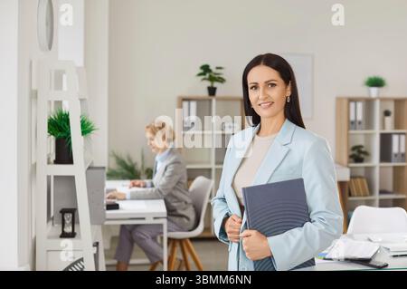 Professionelle Geschäftsfrau in formeller Kleidung posiert mit Notizblock im Büro Stockfoto
