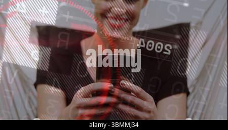 Lächelnde Frau, die in einem modernen Zimmer ein schwarzes Off-Shoulder-Top trägt und ein Smartphone hält, mit Code-Overlays Stockfoto