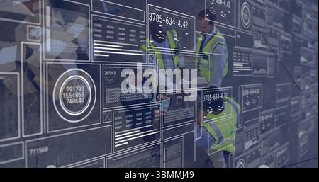 Analyse digitaler Datenschnittstellen und Diagramme, Ingenieure in Sicherheitswesten arbeiten Stockfoto
