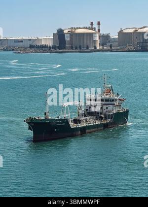 Barcelona, Spanien - 11. Juli 2024: Green Cadiz Fuel Delivery Boot im Hafen mit Enagas hohen Erdgastanks und Meroil Petroleum Tanks hinten Stockfoto
