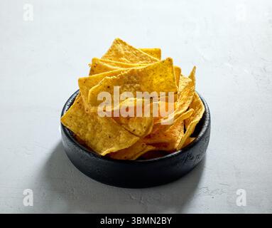 Schüssel mit Tortilla Streifen Nachos Chips auf grauem Tischhintergrund Stockfoto