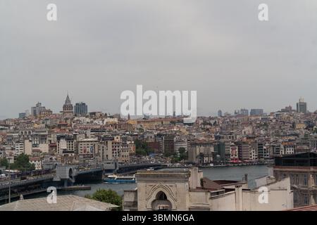 Istanbuls Skyline mit ihrer Mischung aus moderner und historischer Architektur, die die Galata-Brücke vor einem grauen Himmel zeigt. Stockfoto