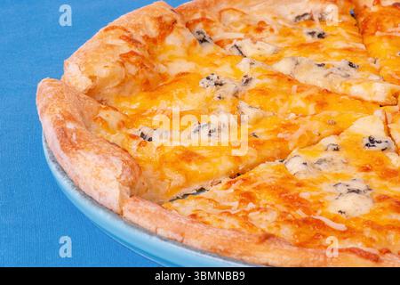 Käsepizza auf blauem Teller. Vier Käse-Pizza auf einer blauen Tischdecke Stockfoto