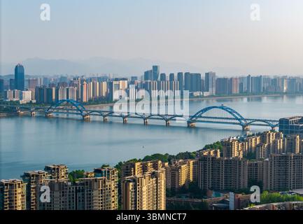 Aus der Vogelperspektive auf eine weitläufige urbane Landschaft mit modernen Gebäuden, einem Fluss und Brücken bei einem wunderschönen Sonnenuntergang. Stockfoto