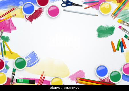 Flaches Design leeres Laken sitzt auf dem Schreibtisch, umgeben von hellen Farbgläsern, Pinseln und Kopierraum Stockfoto