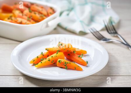 Hausgemachte, geröstete Honig glasierte BabyKarotten mit Thymian, verzehrfertig, selektiver Fokus. Gesundes Wurzelgemüse-Konzept. Stockfoto