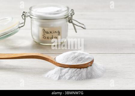 Backpulver in einem Holzlöffel auf einem weißen Holztisch. Stockfoto