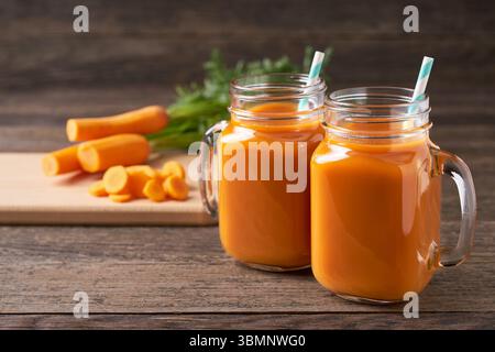 Frischer Karottensaft in einem einmachglas. Szene mit Zutaten vor einem rustikalen Holztisch. Frische Karotten-Smoothies. Stockfoto