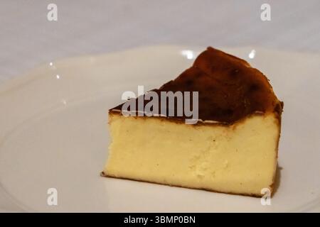 Gebrannter baskischer Käsekuchen, serviert auf dem Teller auf dem Tisch Stockfoto