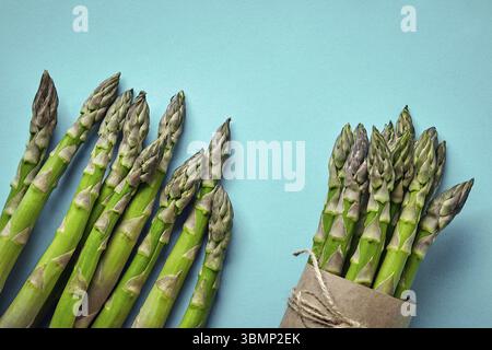Ein Haufen essbarer, reifer Spargel isoliert auf blauem Hintergrund. Frisches, grünes Gemüse, Draufsicht. Gesunde Mahlzeit. Frühlingsernte, agricultura Stockfoto