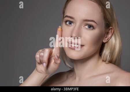 Junge Frau mit Kontaktlinsen auf Zeigefinger mit kopieren. Nahaufnahme Gesicht der gesunden schönen Frau über das Tragen von Kontaktlinsen. Sehvermögen und op Stockfoto
