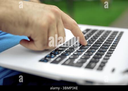 Nahaufnahme der Hände eines gutaussehenden Mannes, der den Bildschirm des Laptops berührt. Geschäftsmann, der einen Laptop benutzt und auf dem Boden sitzt Stockfoto