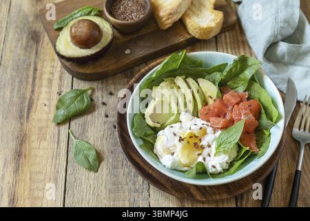 Ketogene, Keto- oder Paläodiät. Köstliches Frühstück oder eine Schüssel mit gesalzenem Lachsfisch, Avocado, gekochtem Ei und Spinat auf einem rustikalen Tisch. Kopieren Sie den SPAC Stockfoto