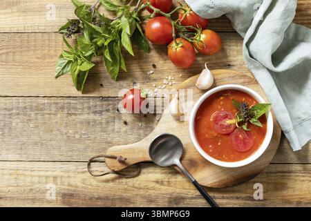 Schüssel Tomatencremesuppe mit Basilikum und Croutons auf einem rustikalen Tisch. Vegane Suppe Püree Tomaten. Gesunde Ernährung Low Carb. Blick von oben. Kopierbereich Stockfoto