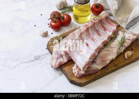 Rohe Kalbsbrust Rippchen Fleisch mit Gemüse und Gewürzen auf kurzen Ersatzrippchen zum Kochen auf Marmorplatte. Kopierbereich Stockfoto