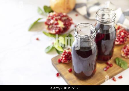 Granatapfelsaft in Glasflaschen und frische Granatapfelfrüchte. Gesunde Getränke Diät Immunität Vitamine oder vegetarisches Lebensmittel Konzept. Kopierbereich Stockfoto