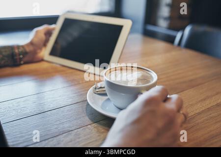 Close up Hände Mann mit Tablet, anschließen. Arbeiten gerade von Cafe. Junger Mann in Smart Casual Wear arbeiten an digitalen tablet, während in der Nähe sitzen Stockfoto