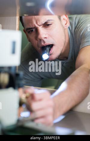 Mechaniker, der an einem Auto mit hellem Licht arbeitet Stockfoto