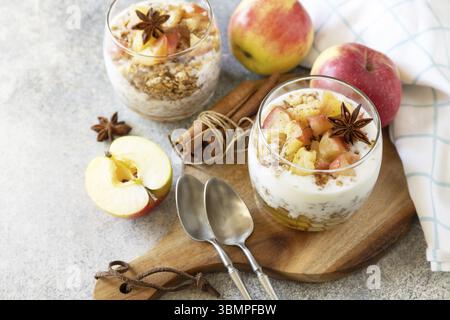 Gesundes Frühstücksmüsli, gesunder Lebensstil. Hausgemachtes Dessert mit Joghurt, Müsli, Karamell-Äpfeln und Zimt auf einem Steintisch. Kopierbereich Stockfoto