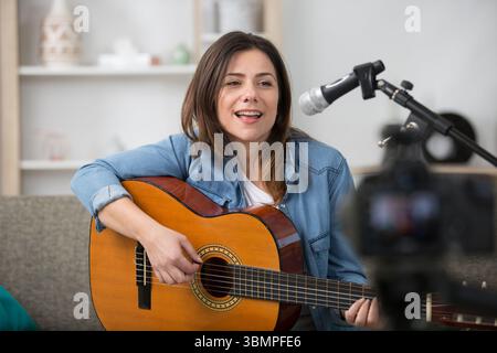 Die Musikerin nimmt sich selbst beim Gitarrenspielen und singen auf Stockfoto